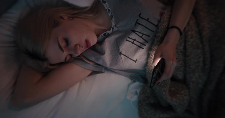 A woman lying in bed tapping on her phone at night