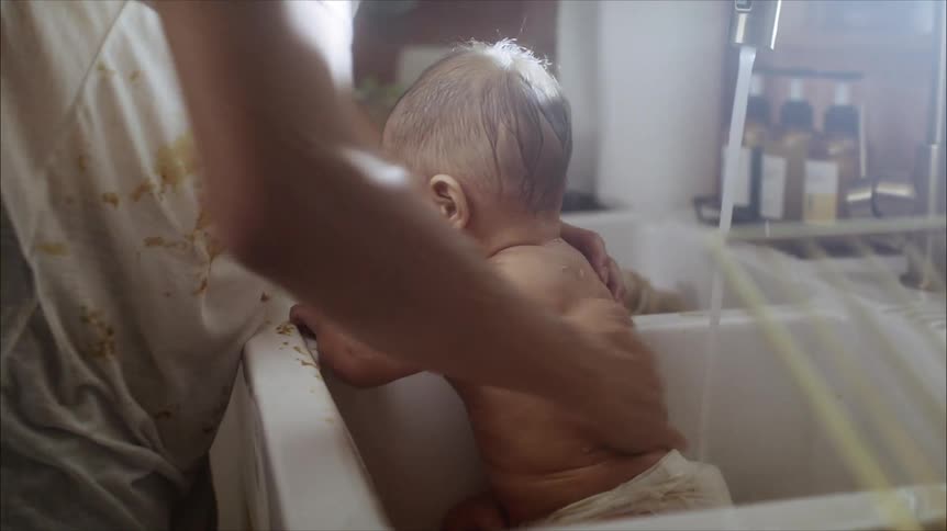 A mother washing her baby in a sink