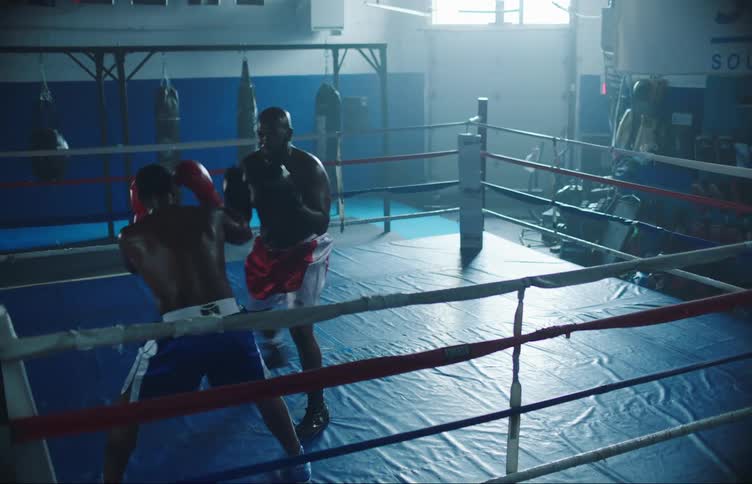 Two men spar in a boxing ring in a gym