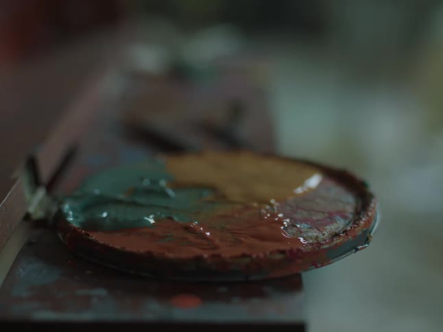 A person picking up paint with a brush