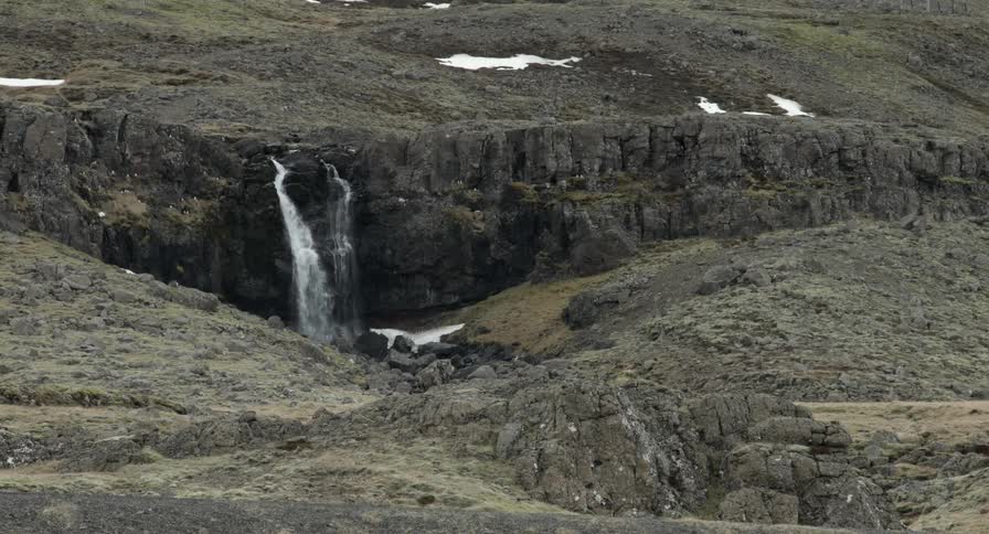 A waterfall drops in the distance