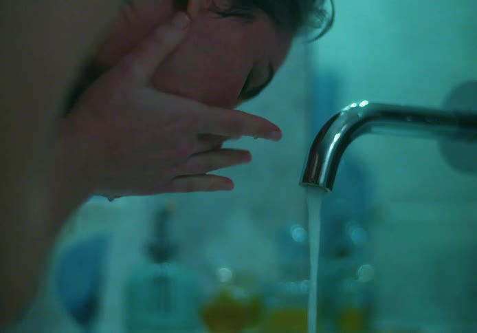 A woman washing her face at a bathroom sink