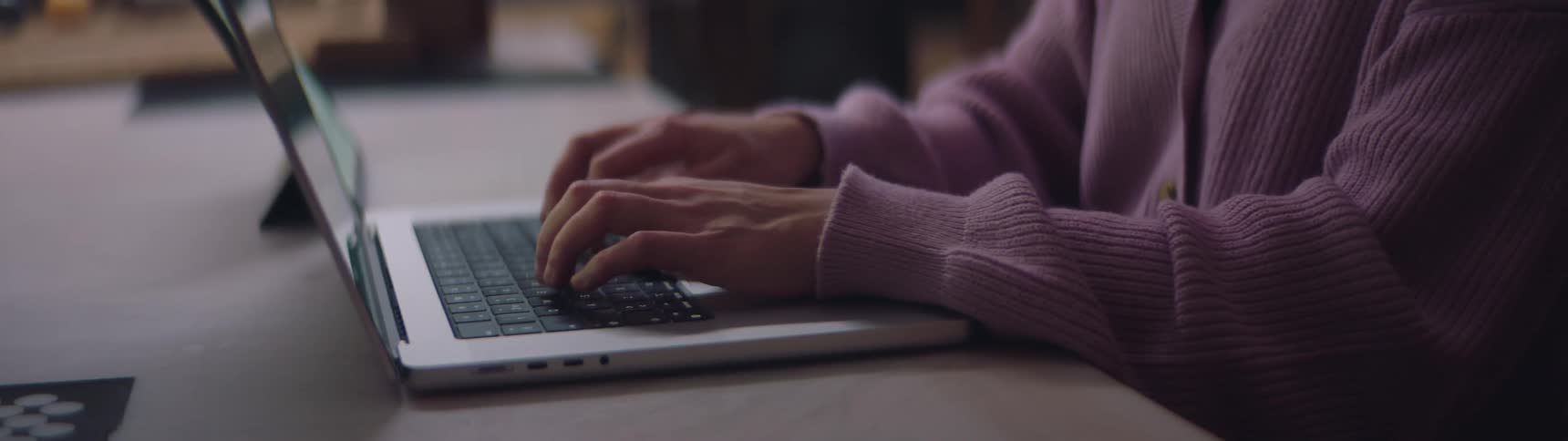 A woman is sitting down and typing on a laptop