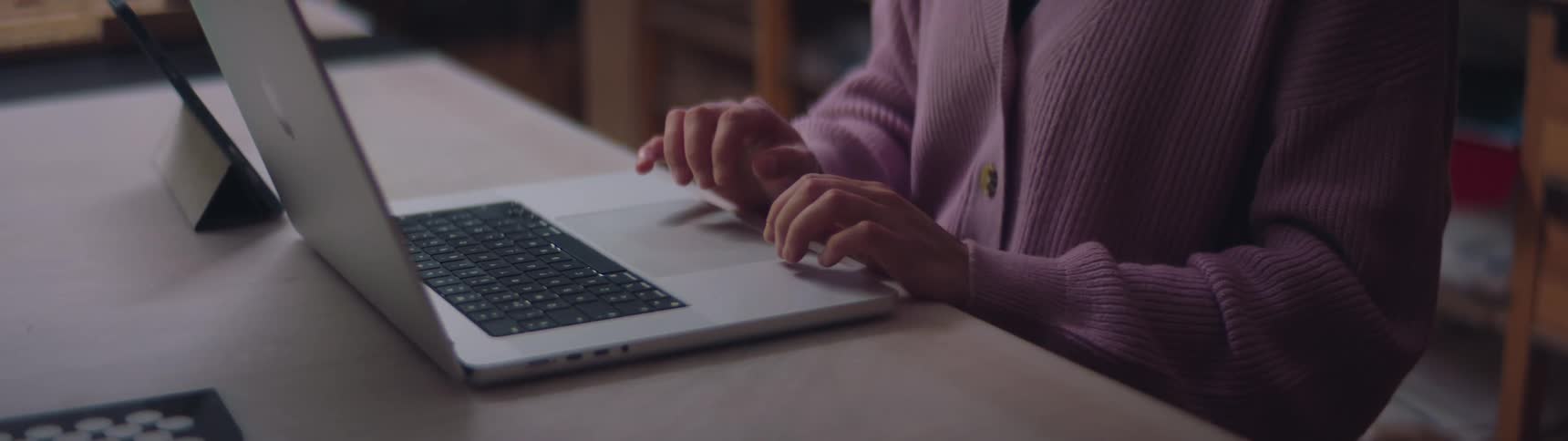 Woman working inside a worksop in front of a laptop near shelves filled with materials
