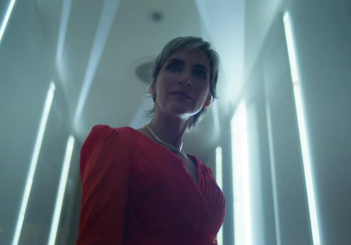 A woman is posing for the camera and wearing a red dress