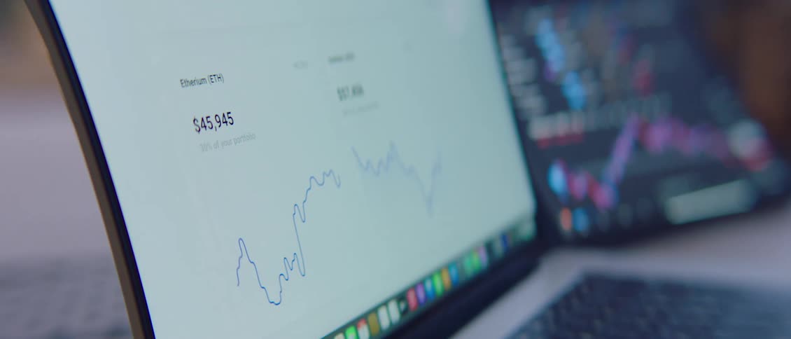 Cryptocurrency graphs on a laptop screen near a tablet scrolling up and down