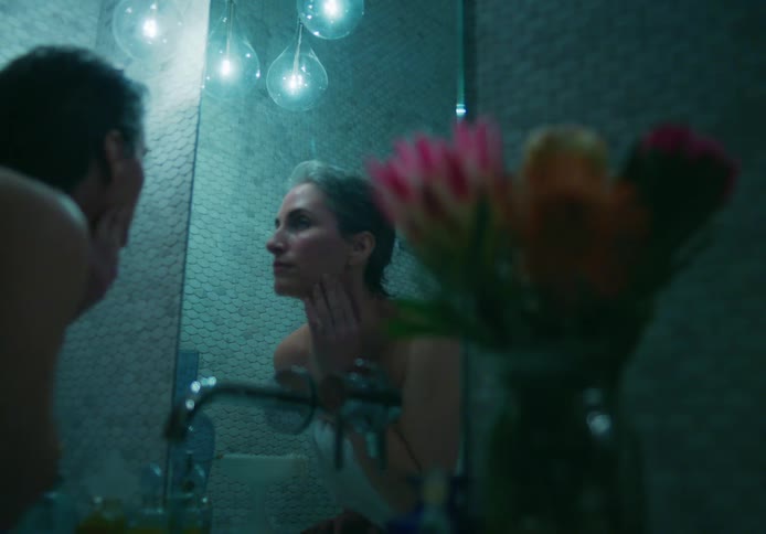 A woman checks her face in the mirror