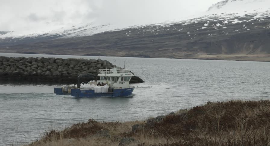 A boat heads out into a larger body of water
