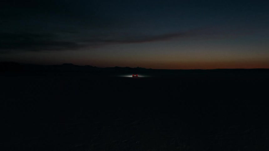 A car is driving fast in an open landscape at night