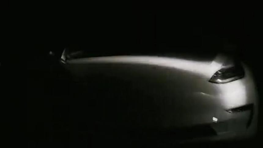 A light shining on a white sports car in darkness