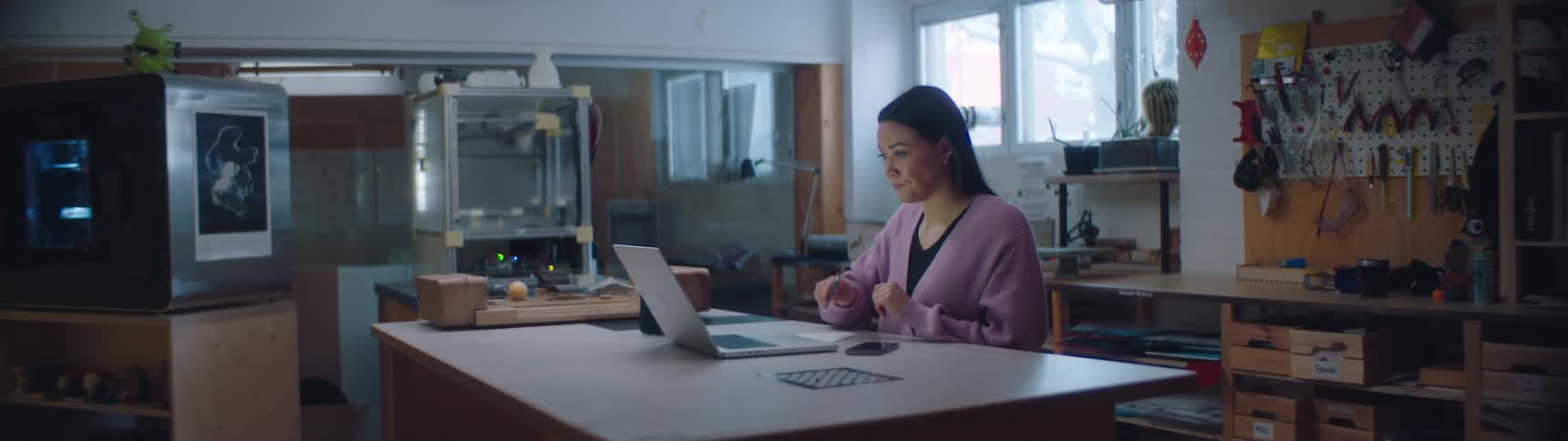 A woman is sitting at a desk typing on a laptop