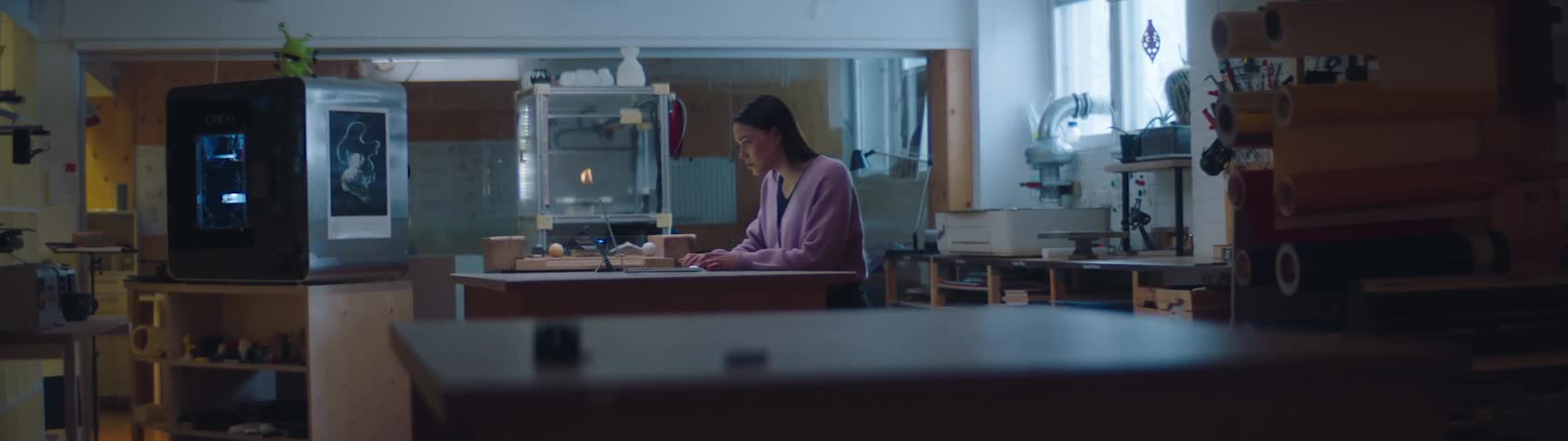 A woman is sitting at a desk in her house with a laptop