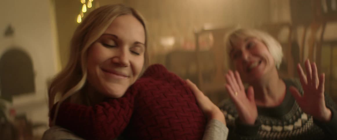 Mom hugs and holds her little boy looking content and happy while grandma talks and smiles