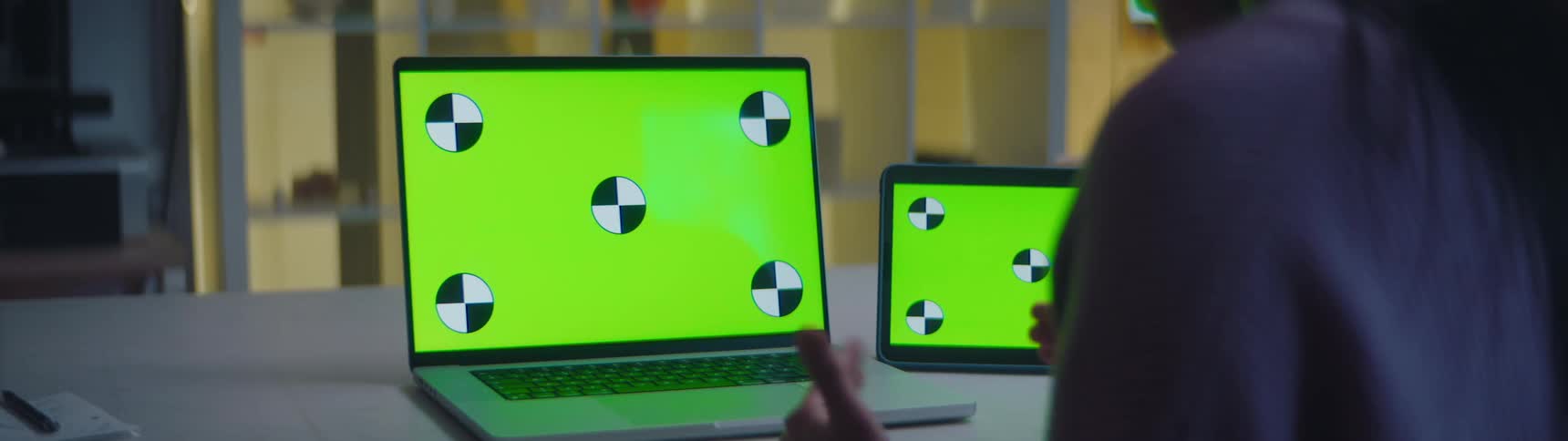 A person is sitting at a desk with two laptops