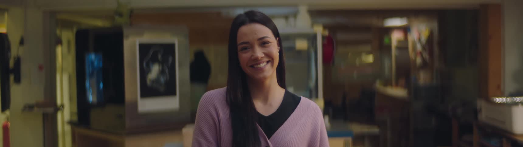 A young woman in a school laughs and smiles
