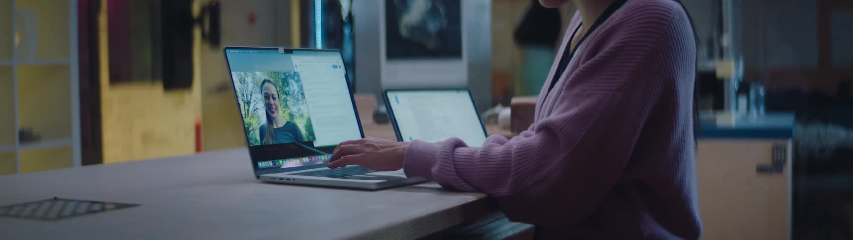 A teenage girl is sitting at a desk having a video conference with another girl on a laptop computer