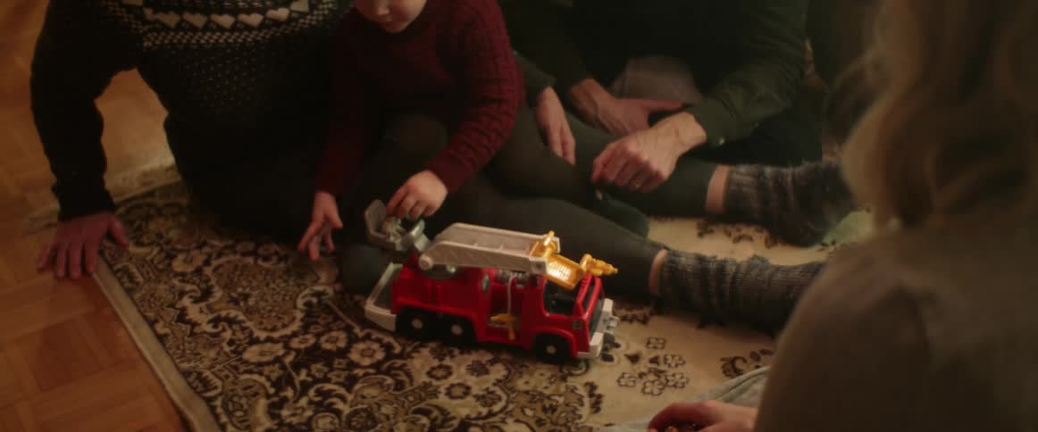 A family watch a boy play with a toy truck