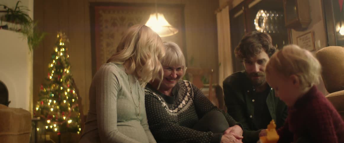 A family is sitting in their living room during the holiday season