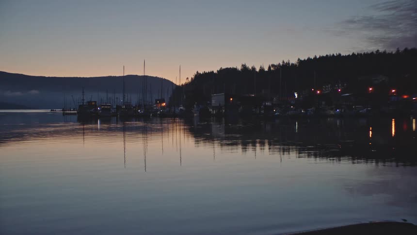 A quiet fishing village is reflected on the water at dusk