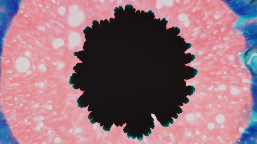 Black liquid spreads over the pink liquid below