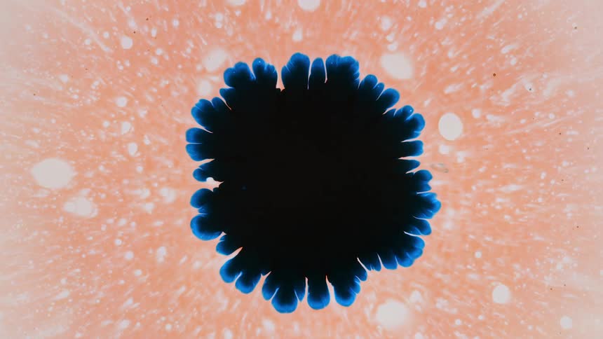 an abstract blue shape of paint expands on a light orange background