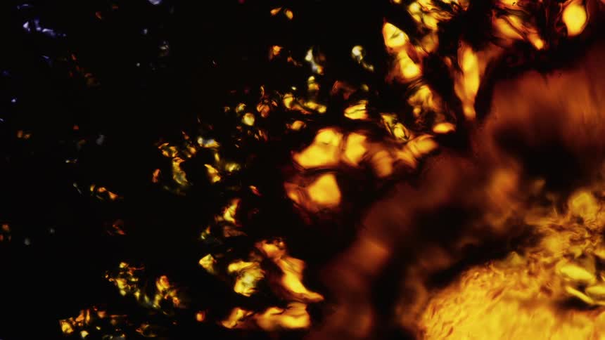 Orange and yellow colors emerge from the edge of a sunlike object with moving textures