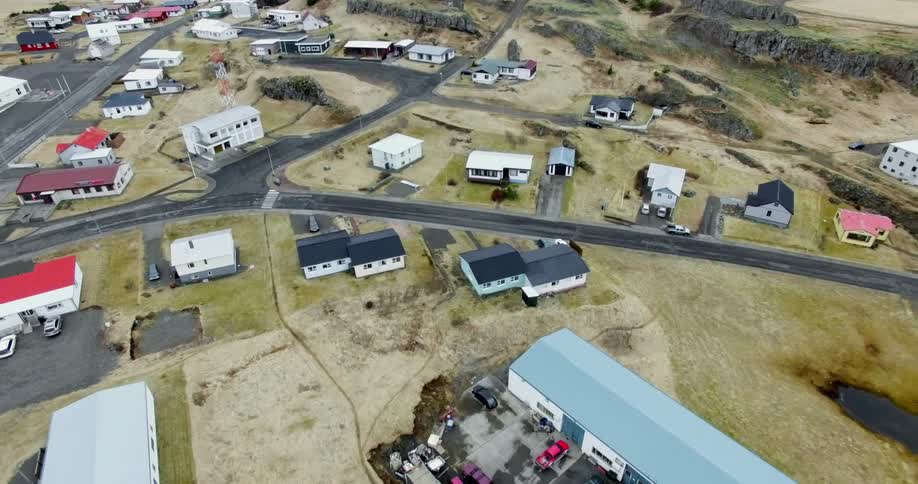 Houses and buildings dot a coastal community landscape as seen from above