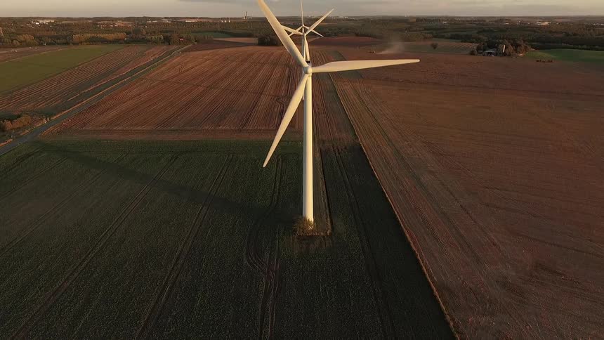 Wind turbines rotate over farm fields