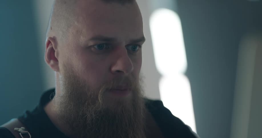 A man in a room looks straight in front of him