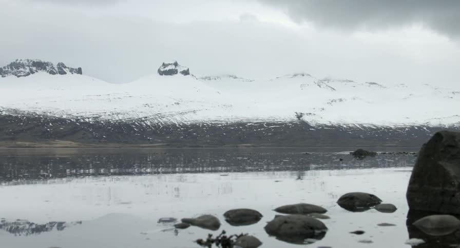 Tide rising in a lake near a snowy hill
