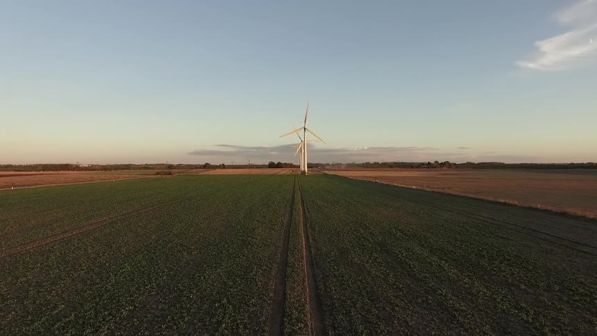 Windmills in a field spin on a clear day