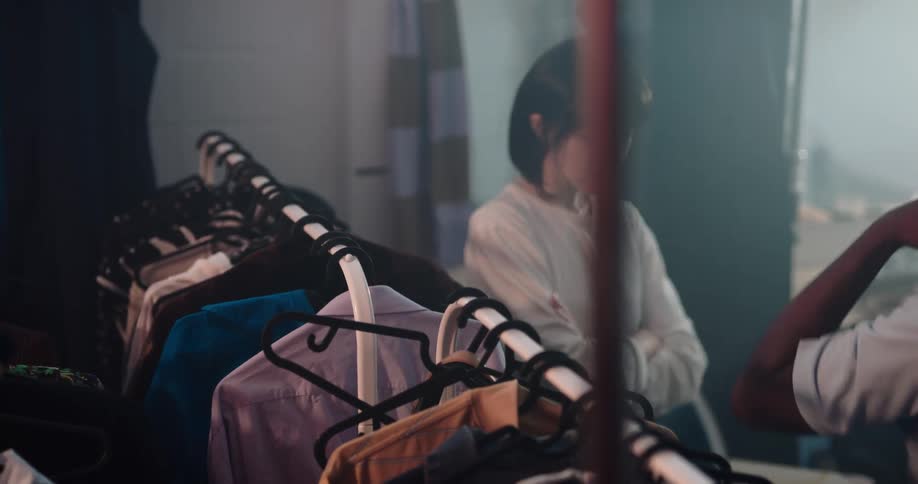 Three people are in a dressing room trying on clothes