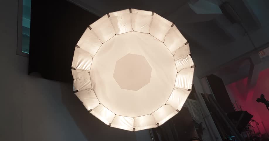 View of a large circular light fixture mounted on a stand in a studio during the evening