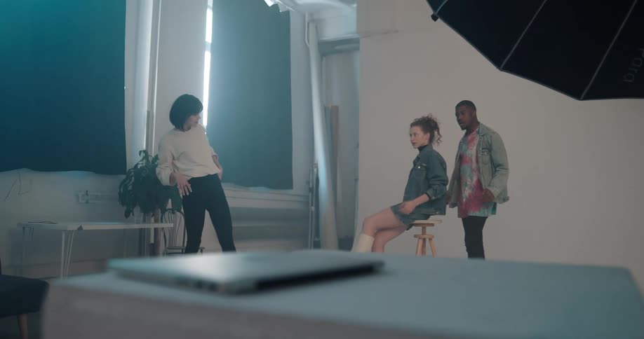 Woman directs models posing for the camera on a photo shoot inside a studio