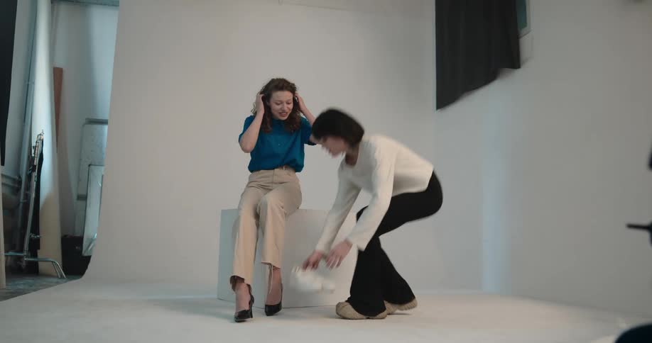 Woman changing the shoes on a model posing for the camera on a photo shoot