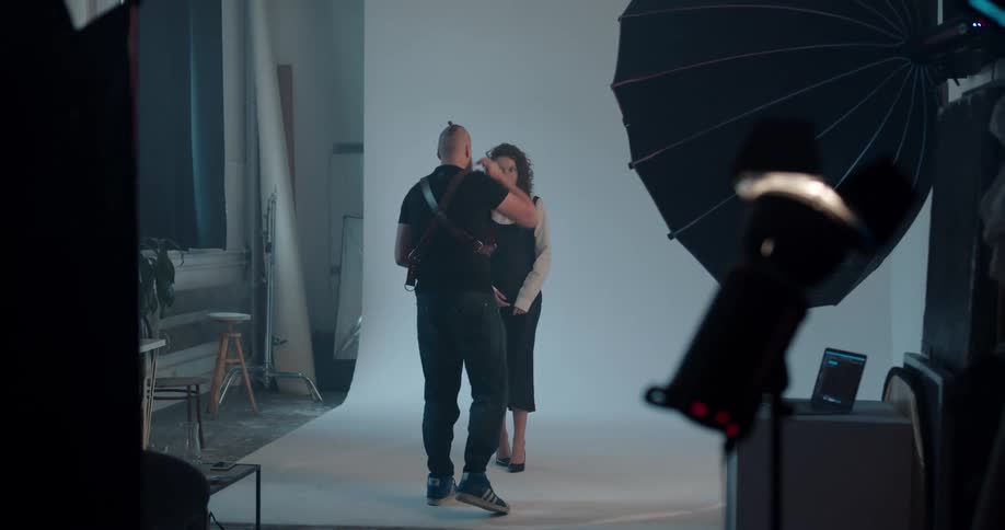 A photographer takes a photo of a woman posing and then walks over to her and gives her instructions