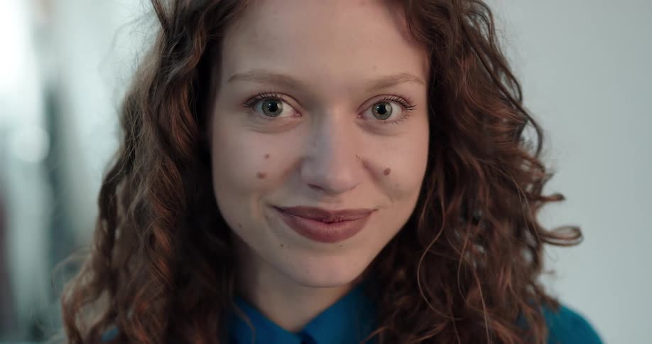 A smiling young woman with curly brown hair