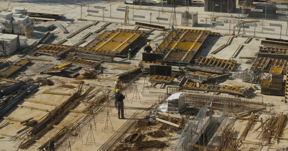 A construction crew is working on a site and taking parts down from a crane