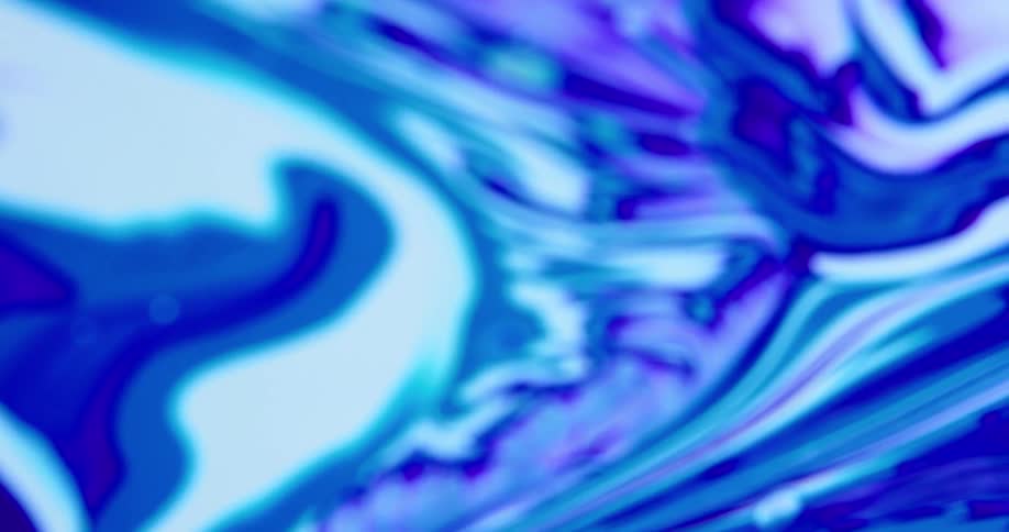Camera spins over a surface covered with streaks and blobs of white and blue liquid ink