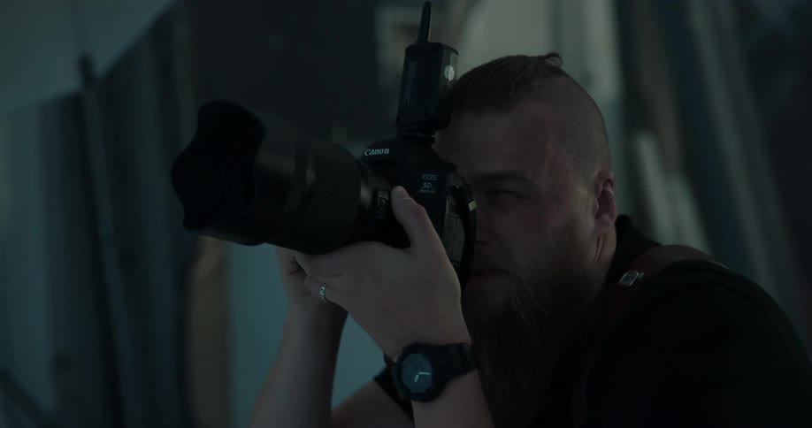 Bearded photographer takes pictures of models while directing them on a photo shoot