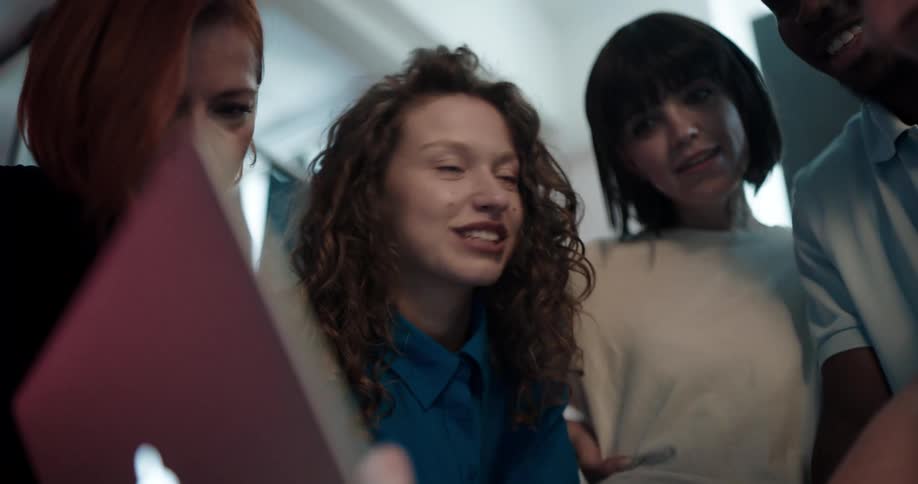 Group of happy excited friends gathered around a laptop looking at the screen