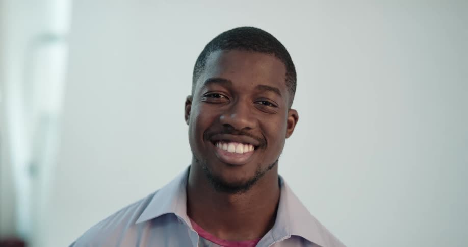 Man standing in front of backdrop in photo set turns and smiles