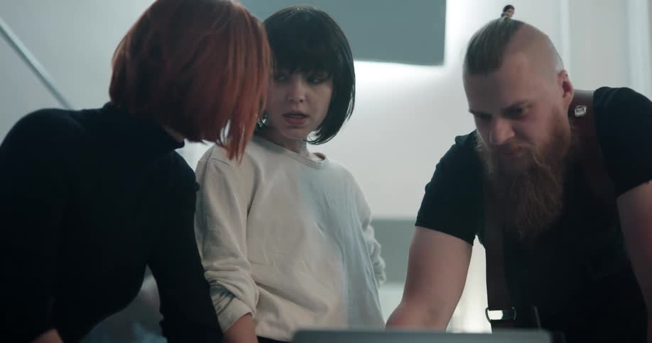 Three friends are talking and looking at a computer screen