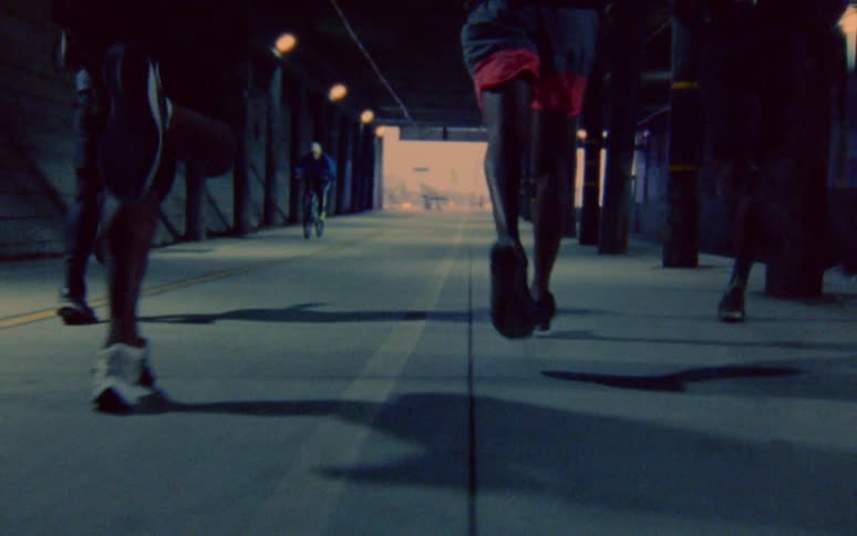 Group of men jogging through a tunnel in the city caught on vintage film