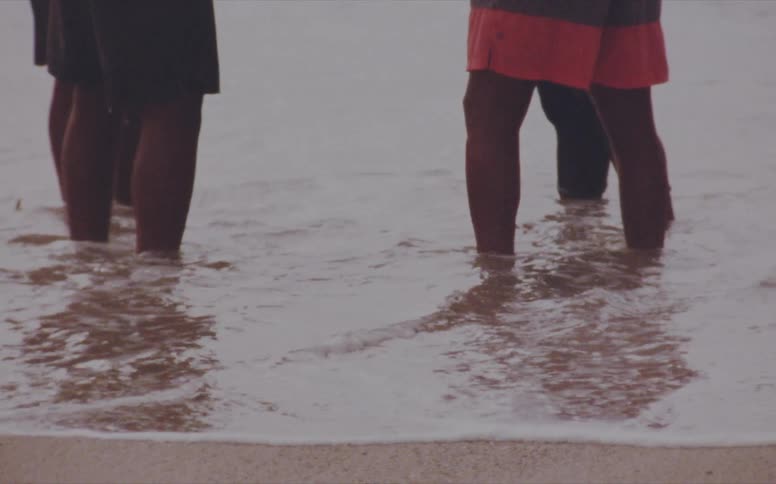 Four people stand in the water of the beach