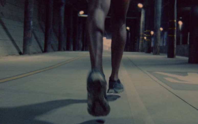 Runner runs through an illuminated tunnel as another runner comes from the opposite direction