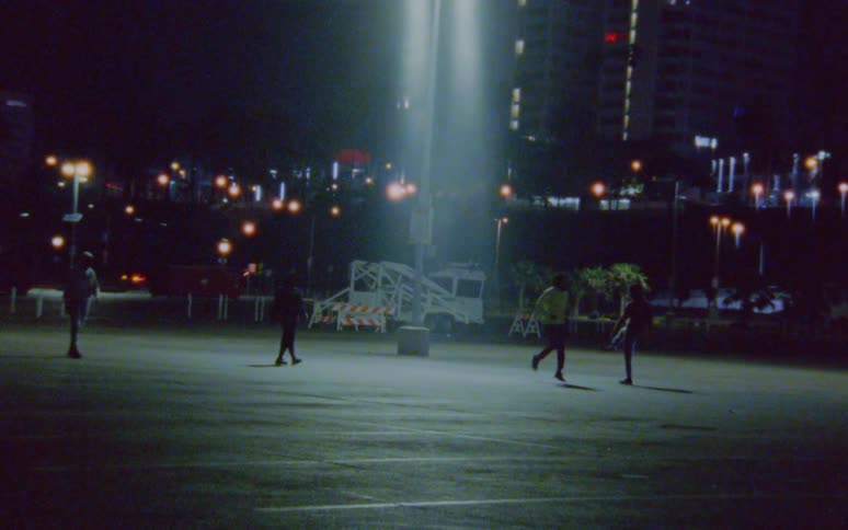 Men run and walk near area lit by parking lot near buildings