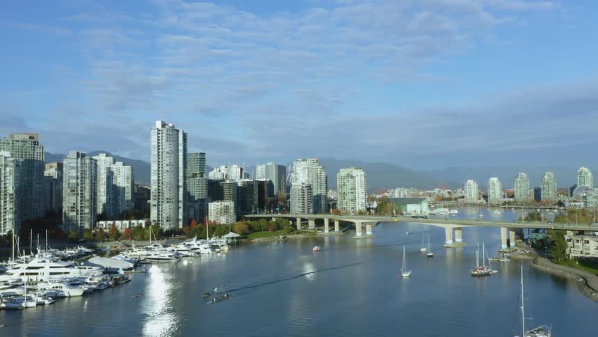 Aerial view of boats floating on a river in front of the the skyscrapers in Vancouver