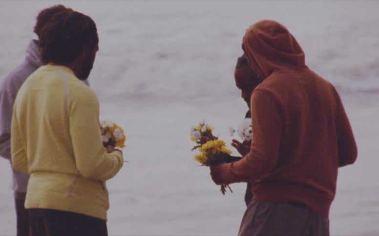 Men hold flowers on the beach