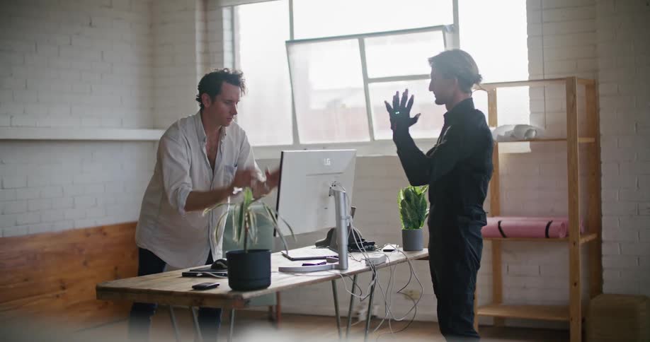 Man in white shirt gives instructions to another man wearing a futuristic motion capture black suit